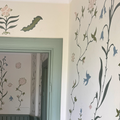Handmålat tapetmönster med blommor, blad och fåglar i Julia Sundby af Robsons stil, i en dörröppning