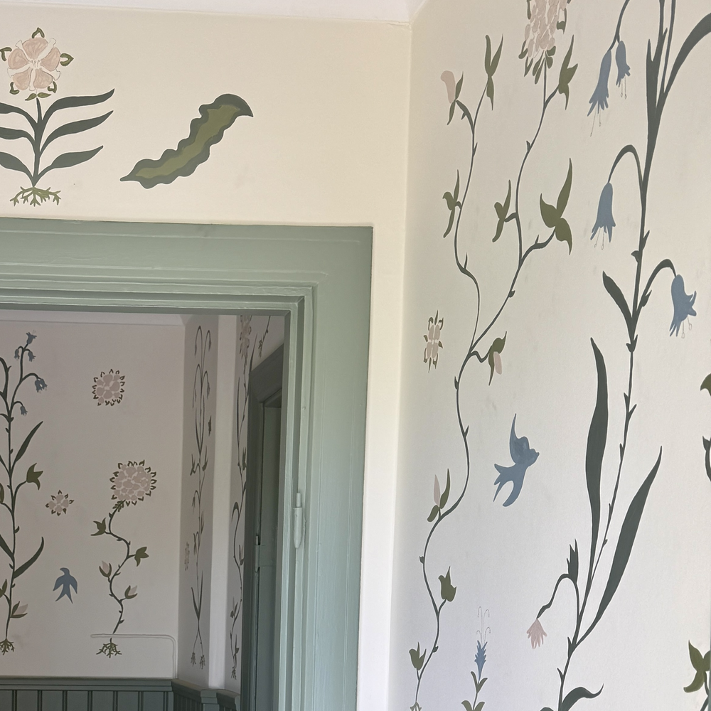 Handmålat tapetmönster med blommor, blad och fåglar i Julia Sundby af Robsons stil, i en dörröppning